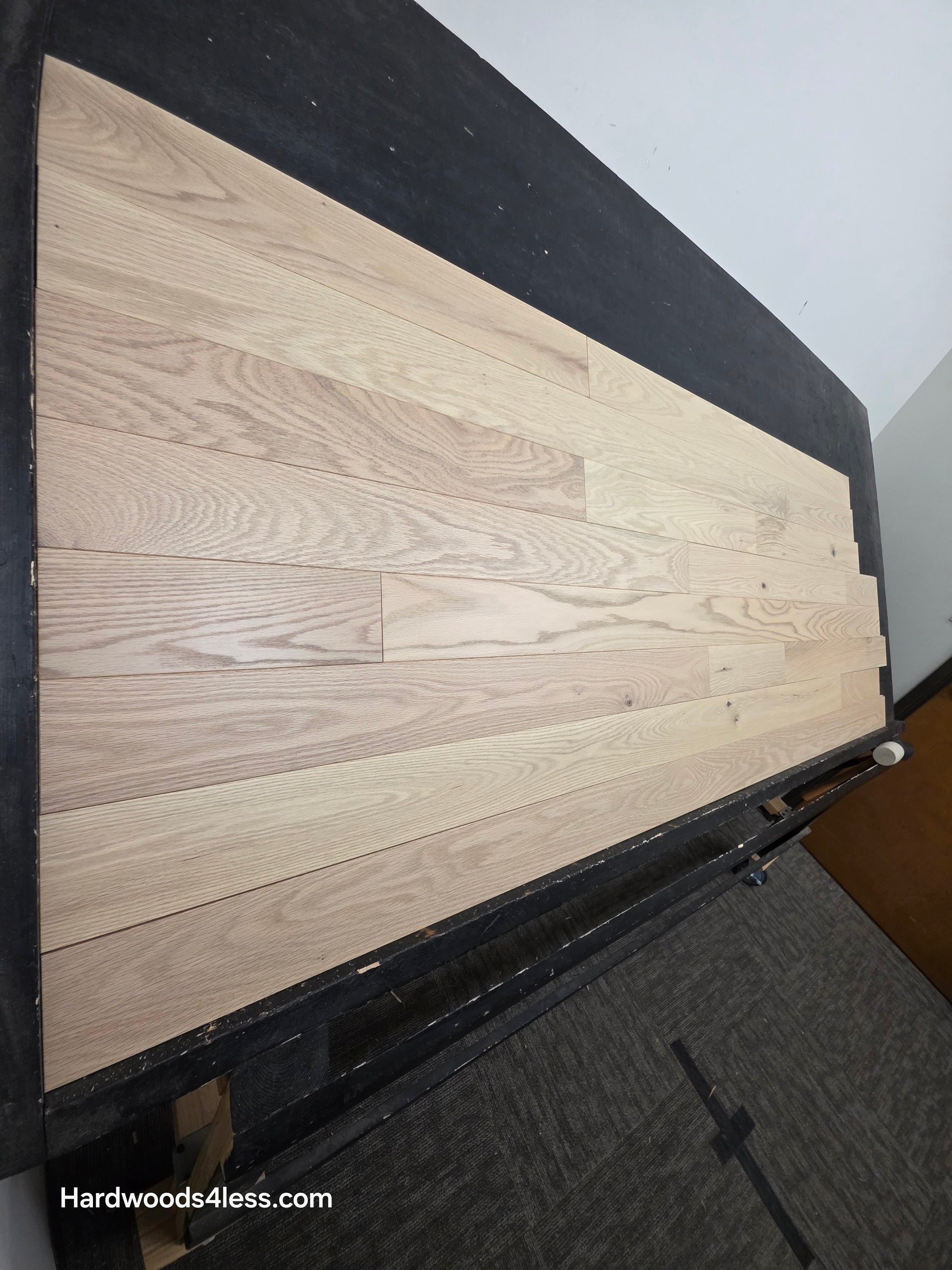 4" x 3/4" Solid Red Oak Doe Hardwood Flooring. Shown on a black shooting table. Shot from steep left.
