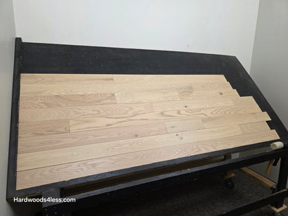 4" x 3/4" Solid Red Oak Doe Hardwood Flooring. Shown on a black shooting table. Shot from wide left.