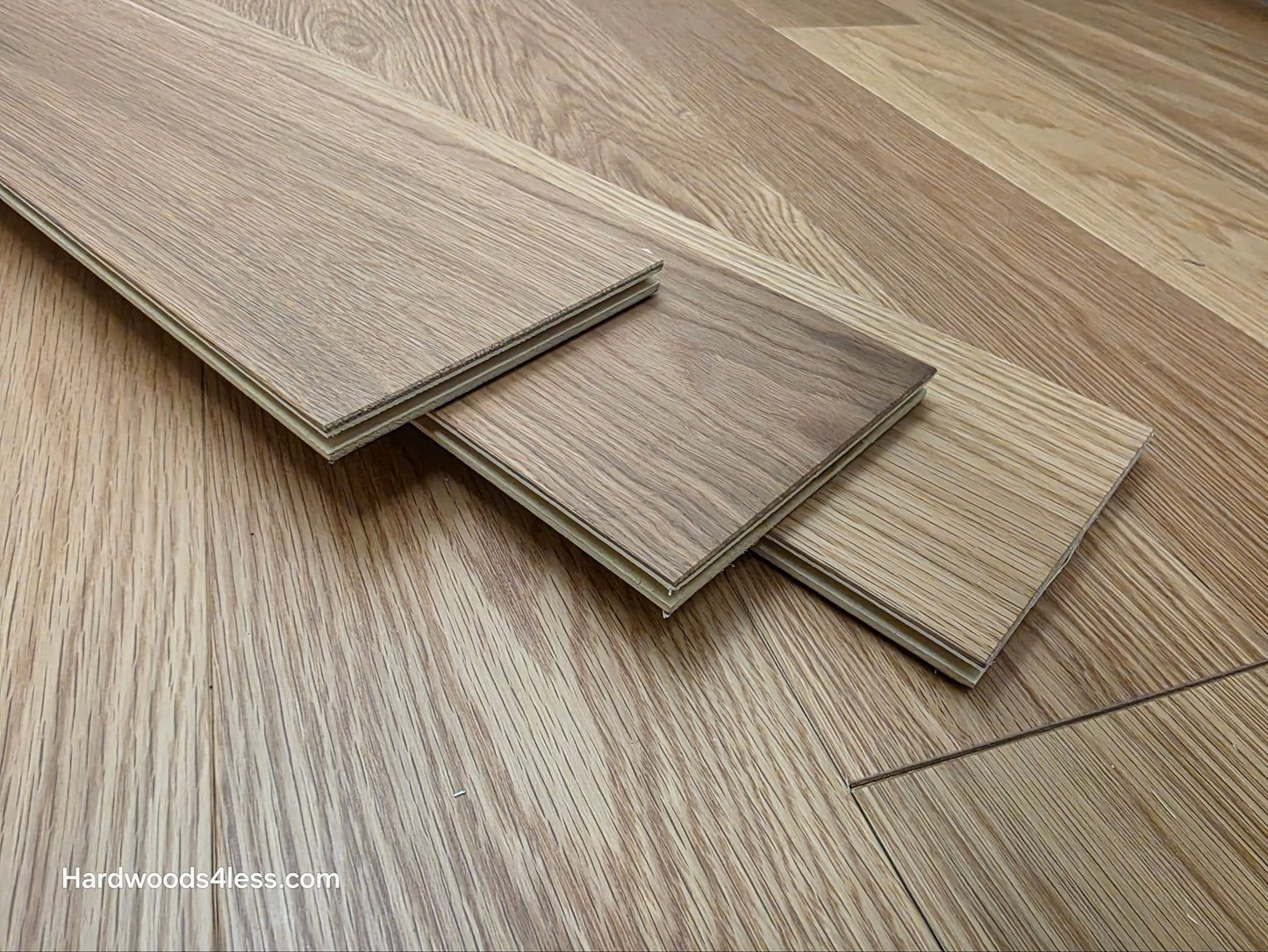 5 1/8" x 1/2"  Engineered White Oak Select & Better Natural Hardwood Flooring. Shown as three boards stacked on top of the floor. 