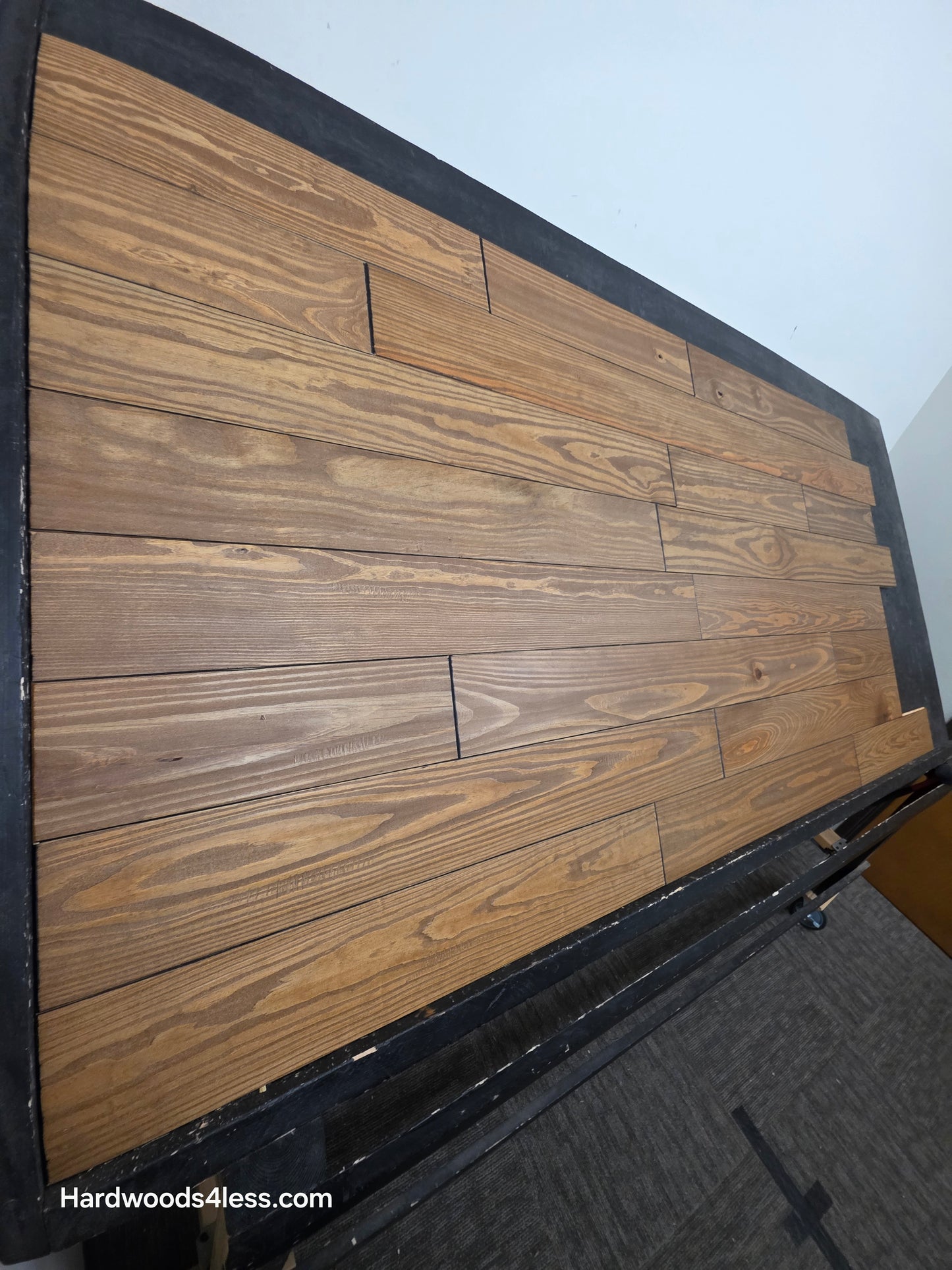 5 1/8" x 3/4" Southern Yellow Pine Ginger Solid Hardwood Flooring. Shown on a black shooting table. Steep left hand shot.