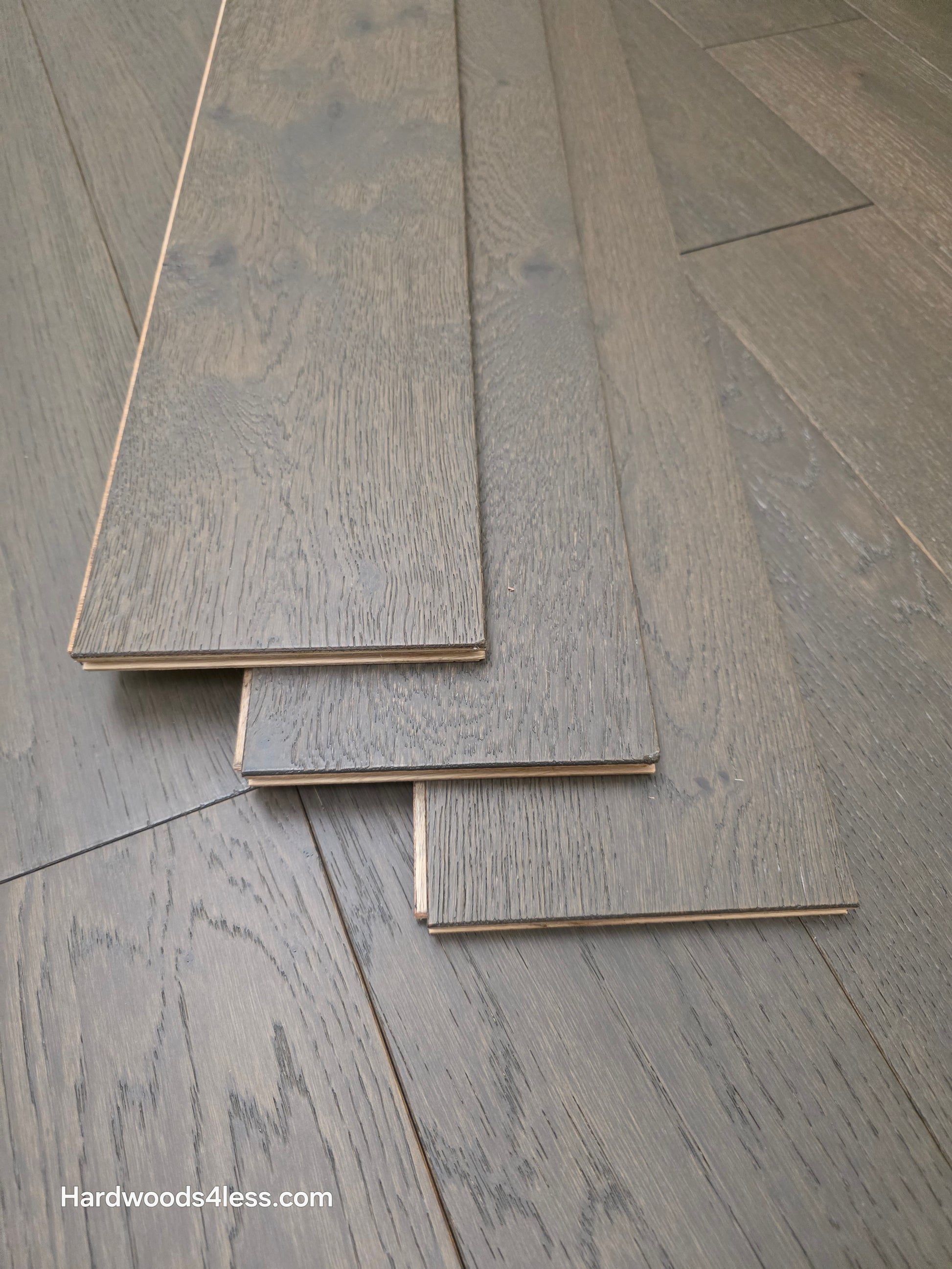 5 7/8" x 9/16" Engineered European Oak Mount Mitchell Hardwood Flooring. Shown with three boards stacked atop the flooring. 