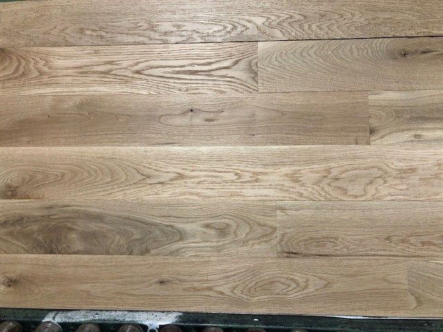 5" x 3/4" Unfinished White Oak #1 Common Solid Hardwood Flooring shown on a green shooting table with rollers at the base 