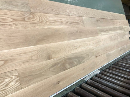 5" x 3/4" Unfinished White Oak #1 Common Solid Hardwood Flooring shown on a green shooting table with rollers at the base 