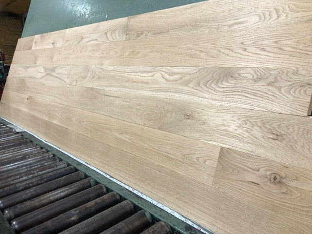 5" x 3/4" Unfinished White Oak #1 Common Solid Hardwood Flooring shown on a green shooting table with rollers at the base 