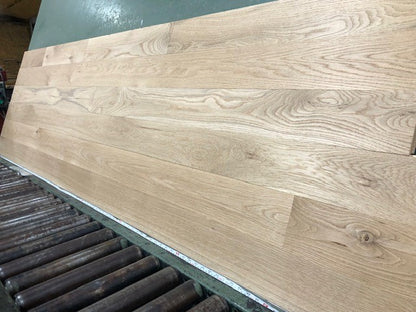 5" x 3/4" Unfinished White Oak #1 Common Solid Hardwood Flooring shown on a green shooting table with rollers at the base 