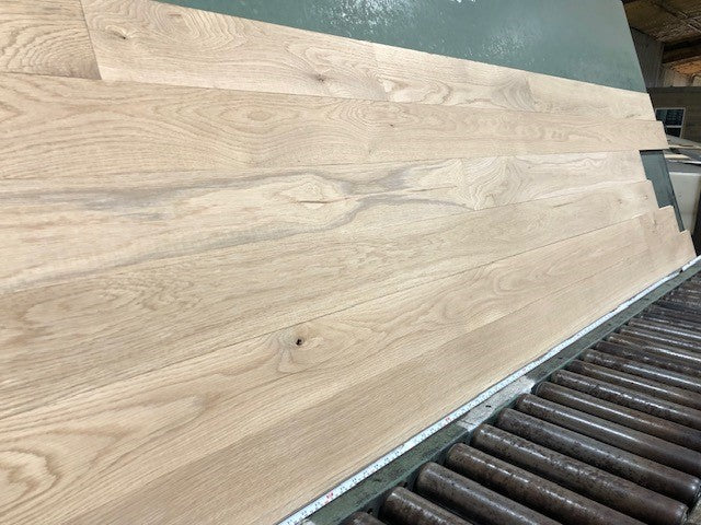 5" x 3/4" Unfinished White Oak #1 Common Solid Hardwood Flooring shown on a green shooting table with rollers at the base 