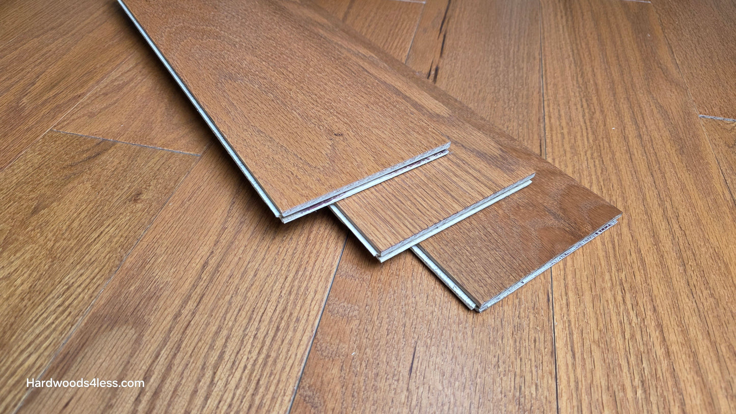 5" x 1/2" Engineered Red Oak Golden Oak Hardwood Flooring. Three wood flooring planks are shown at center. The planks are sitting on top of the Golden Oak flooring. 