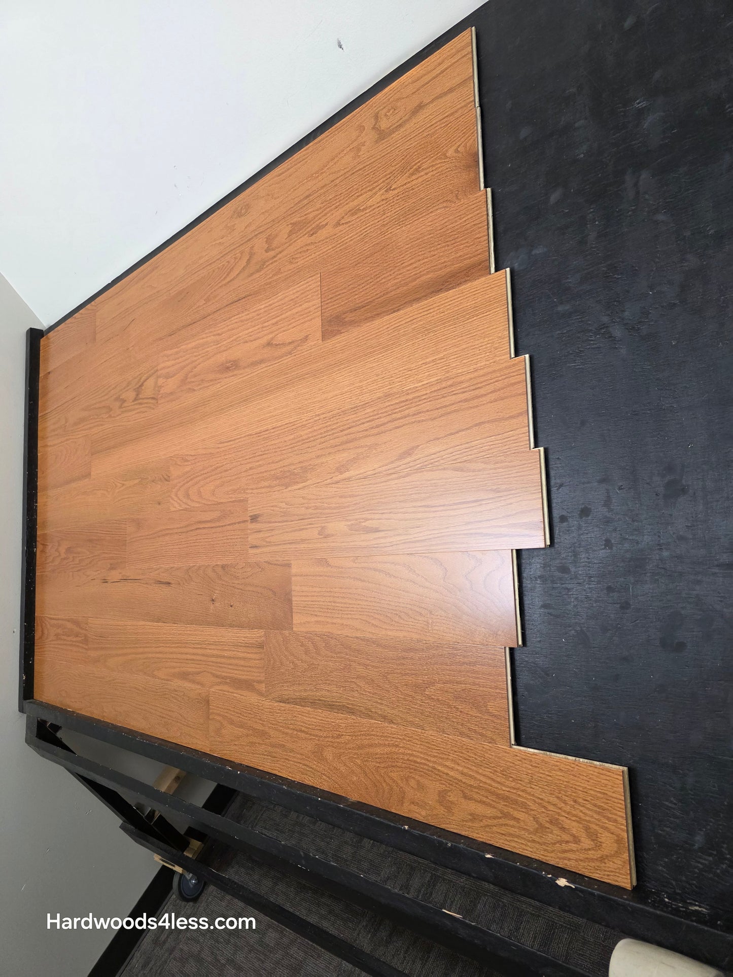 5" x 1/2" Engineered Red Oak Golden Oak Hardwood Flooring. Shown on a black shooting table. Shot from steep right.