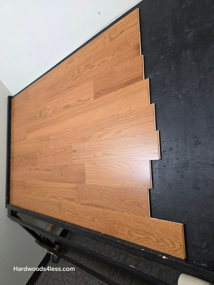 5" x 1/2" Engineered Red Oak Golden Oak Hardwood Flooring. Shown on a black shooting table. Shot from steep right.