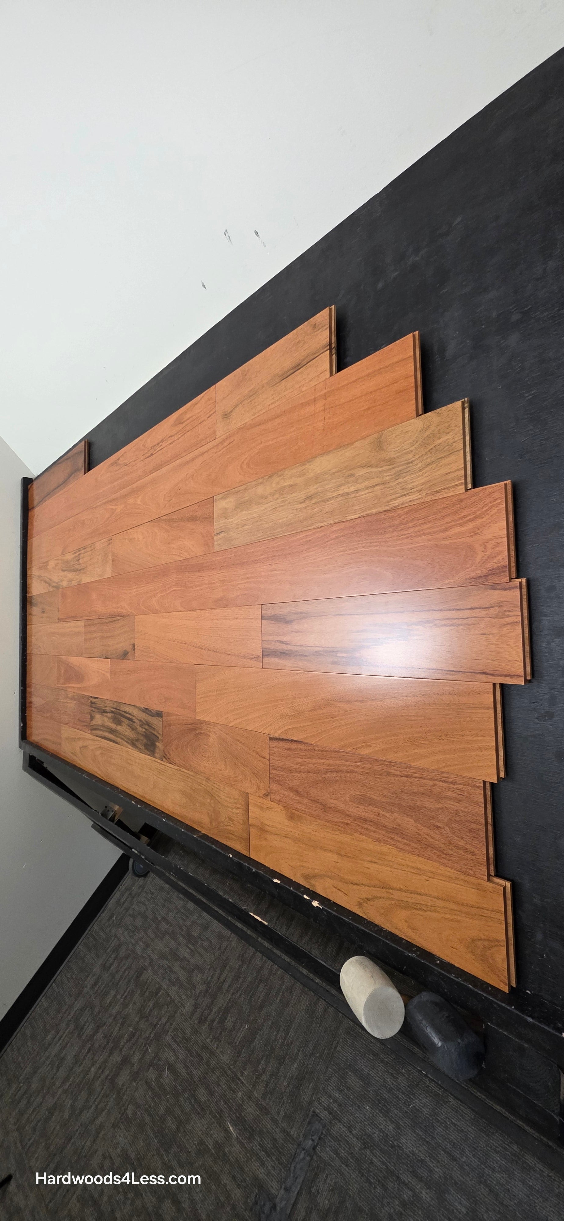 5" x 3/4" Prefinished Brazilian Cherry Shorts Hardwood Flooring. Shown on a black shooting table. Shot from steep right.