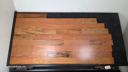 5" x 3/4" Prefinished Brazilian Cherry Shorts Hardwood Flooring. Shown on a black shooting table. Shot from center. 