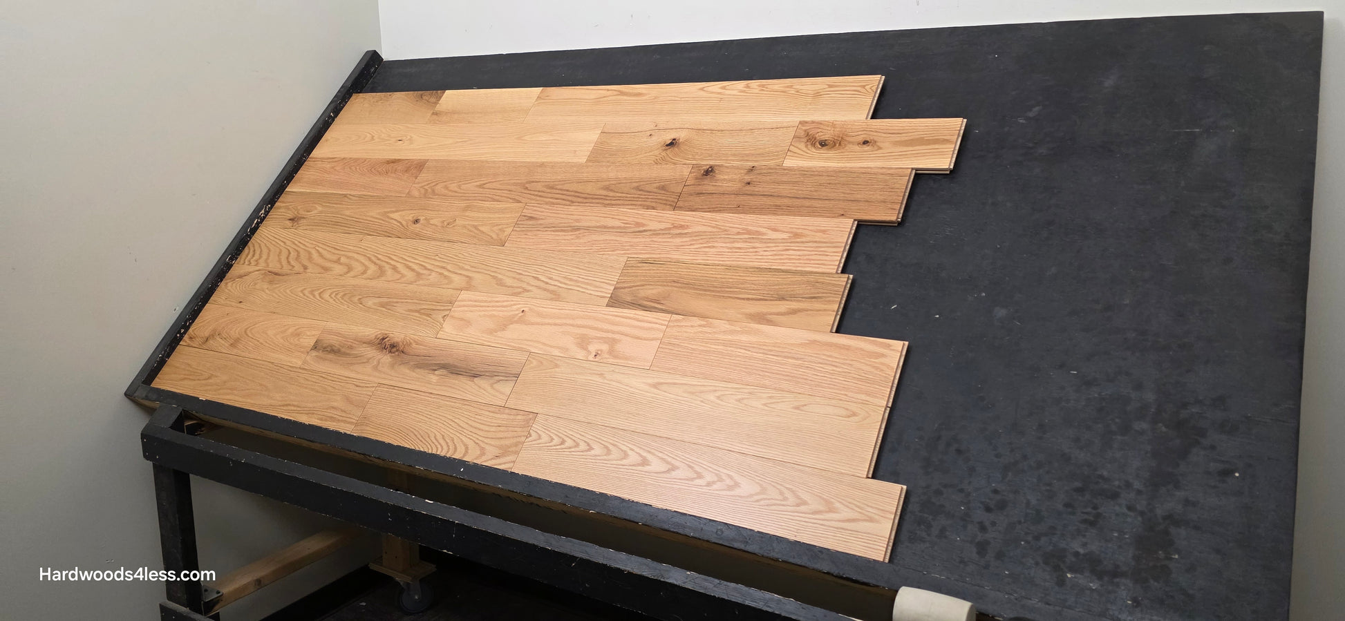5" x 3/4" Solid Red Oak Low Gloss Common & Better Hardwood Flooring. Shown on a black shooting table. Shot wide right. 