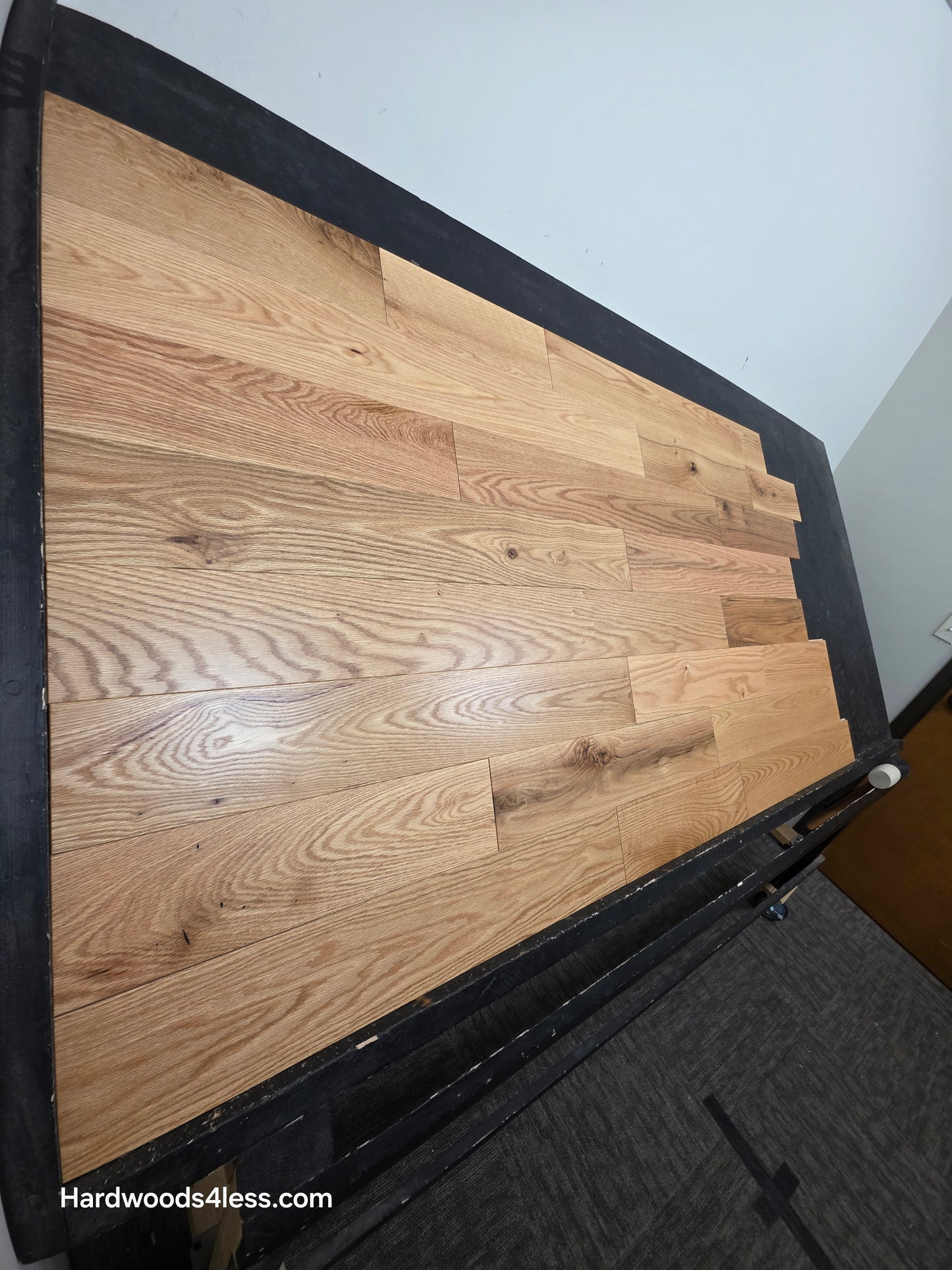 5" x 3/4" Solid Red Oak Low Gloss Common & Better Hardwood Flooring. Shown on a black shooting table. Shot steep left. 