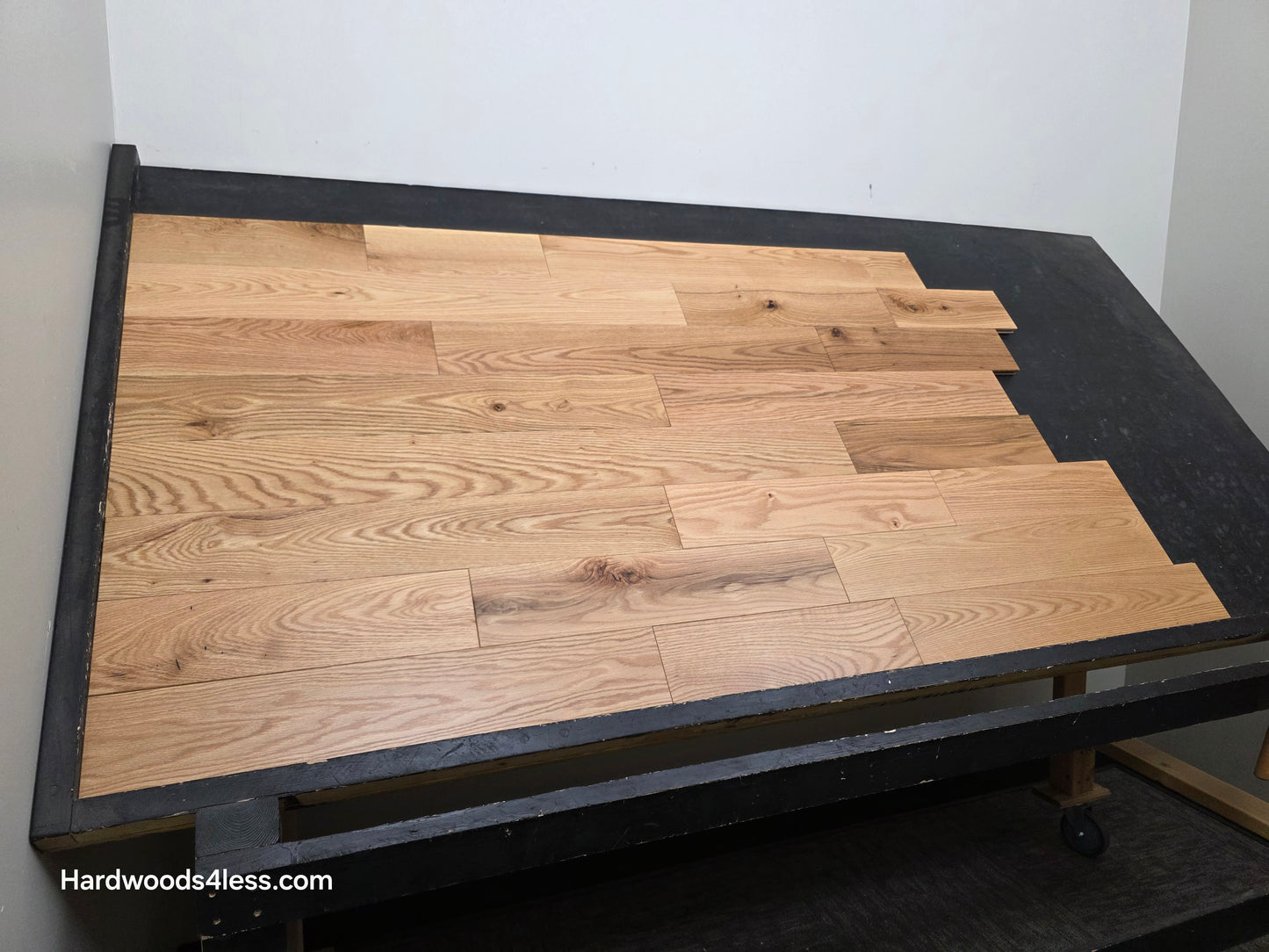 5" x 3/4" Solid Red Oak Low Gloss Common & Better Hardwood Flooring. Shown on a black shooting table. Shot wide left. 