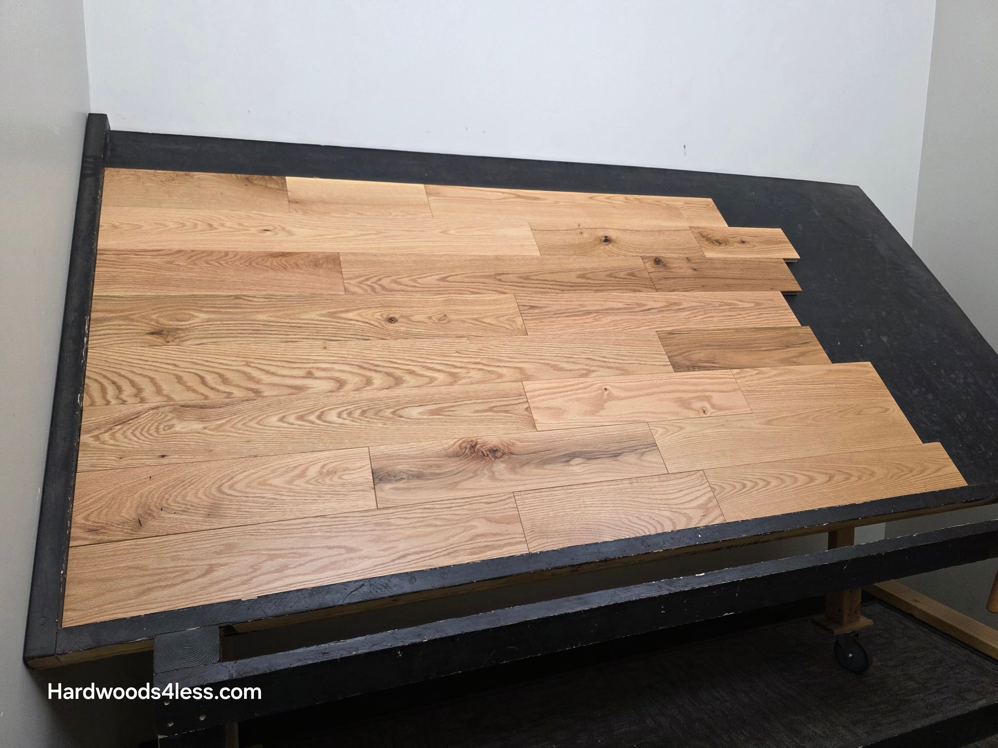 5" x 3/4" Solid Red Oak Low Gloss Common & Better Hardwood Flooring. Shown on a black shooting table. Shot wide left. 