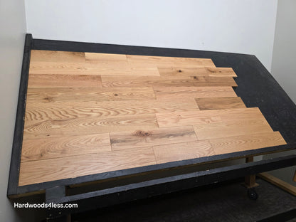 5" x 3/4" Solid Red Oak Low Gloss Common & Better Hardwood Flooring. Shown on a black shooting table. Shot wide left. 