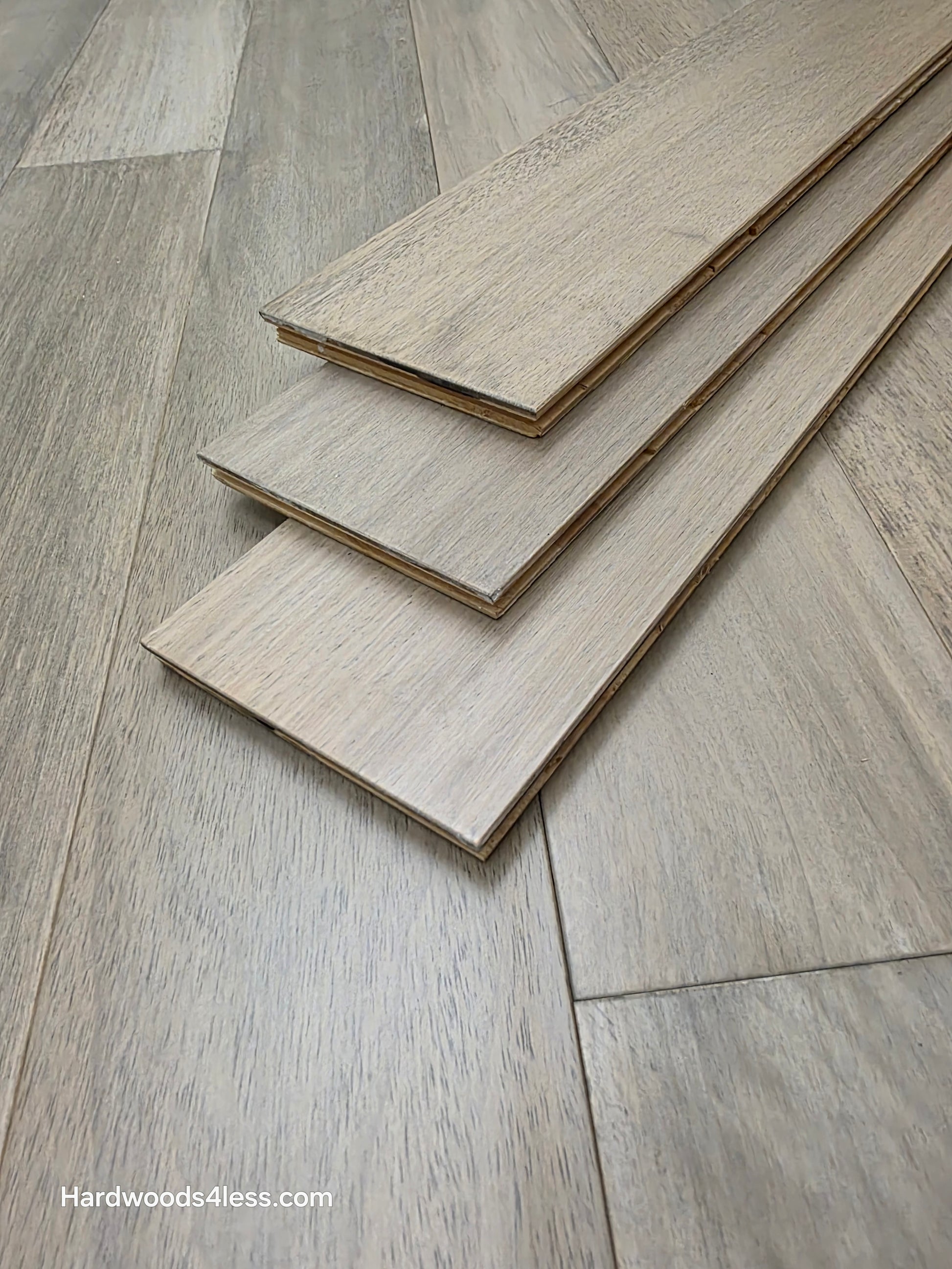 5" x 9/16" Engineered Brazilian Oak Light Grey Hardwood Flooring. Shown as 3 planks laid on top of each other on the flooring. 