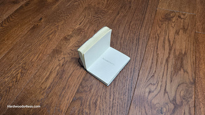 6 1/2" x 1/2" Engineered European White Oak Old Fashioned Hardwood Flooring. Shown with a small book, with the words, Hardwoods4less, Written in the center. 