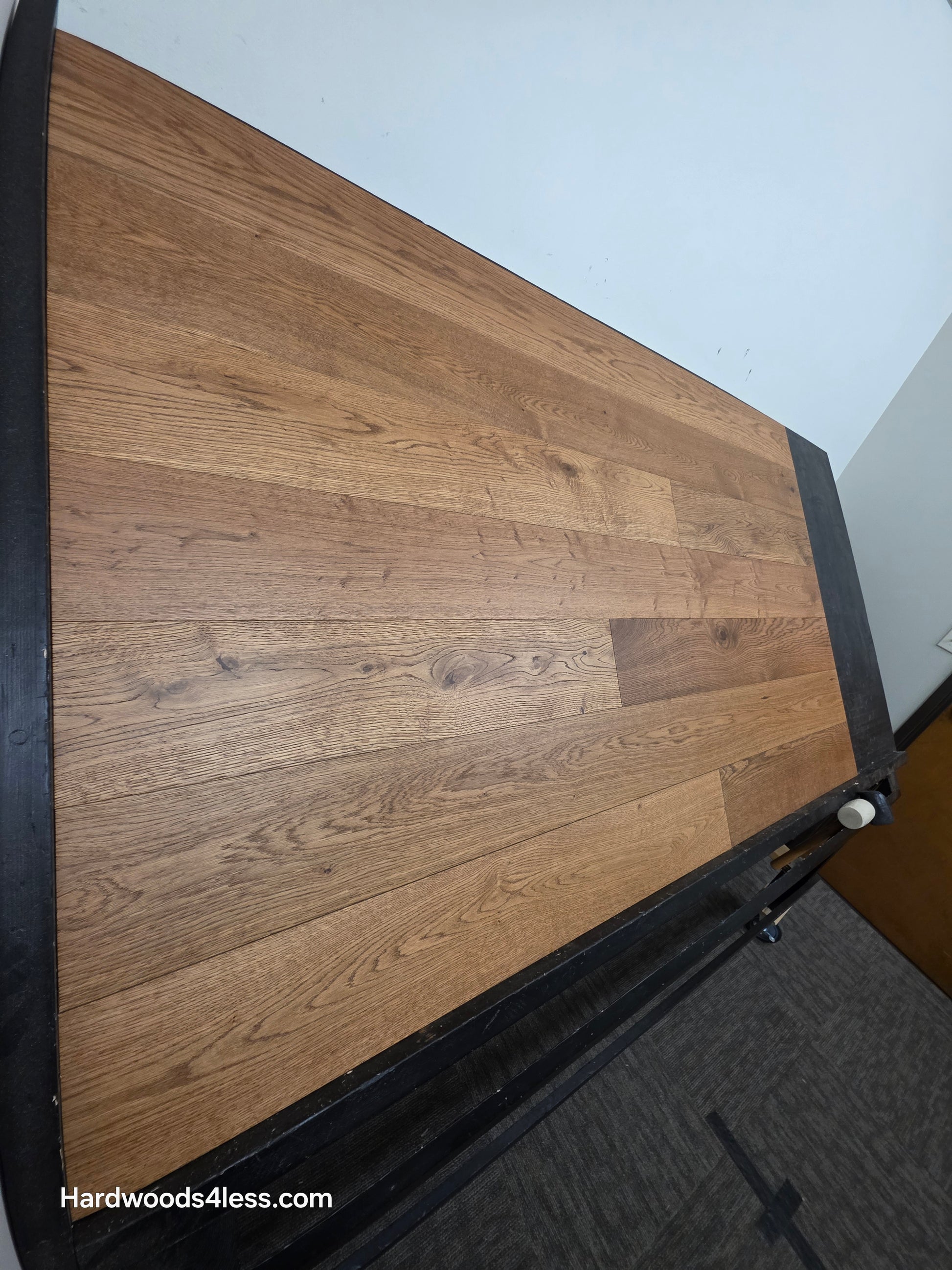 6 1/2" x 1/2" Engineered European White Oak Tequila Sunrise Hardwood Flooring. Shown on a black shooting table. Shot from steep left.