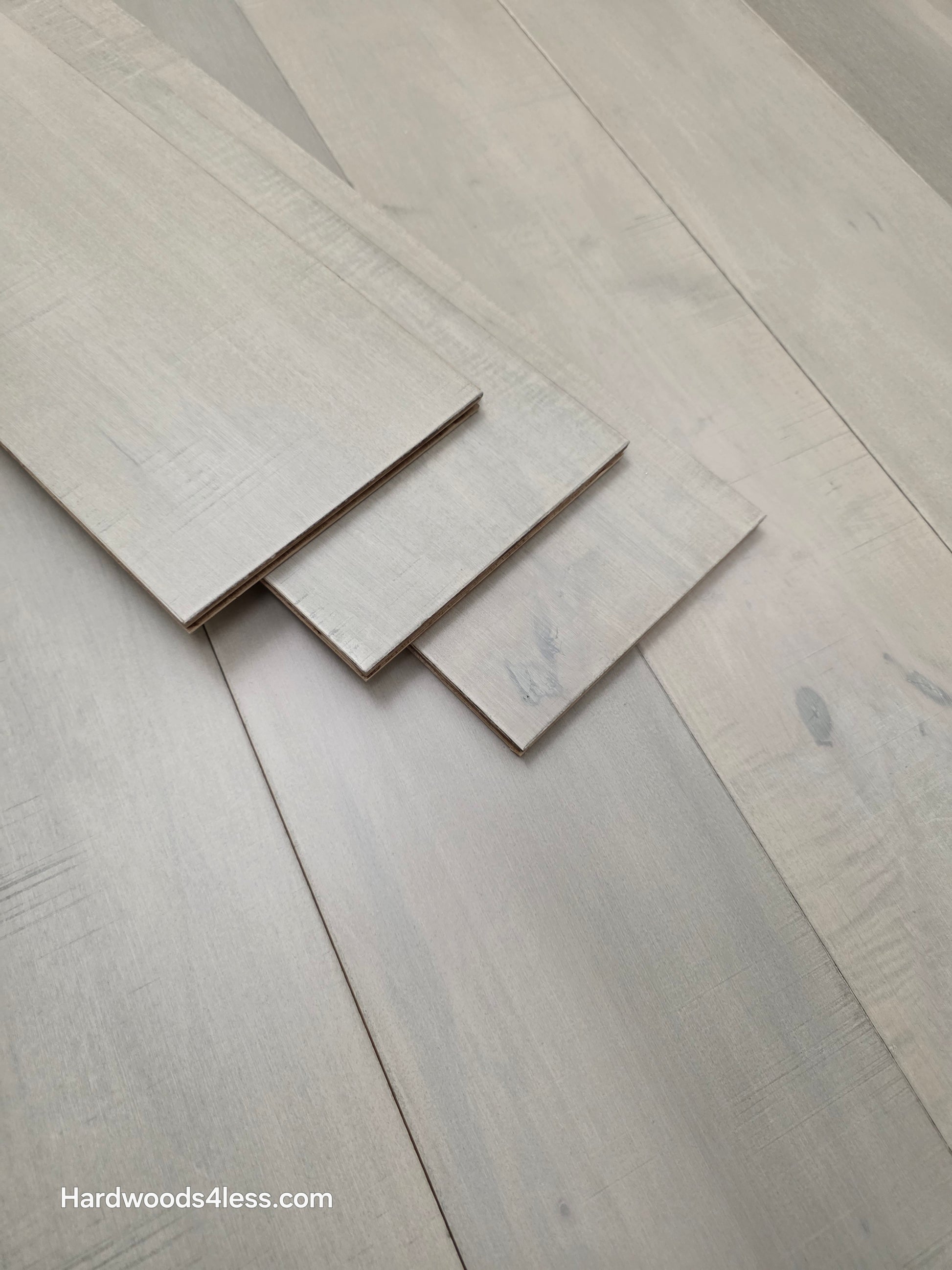 6 1/2" x 1/2" Engineered Maple Misty Moonlight Hardwood Flooring shown with three extra boards stacked on top of the floor.