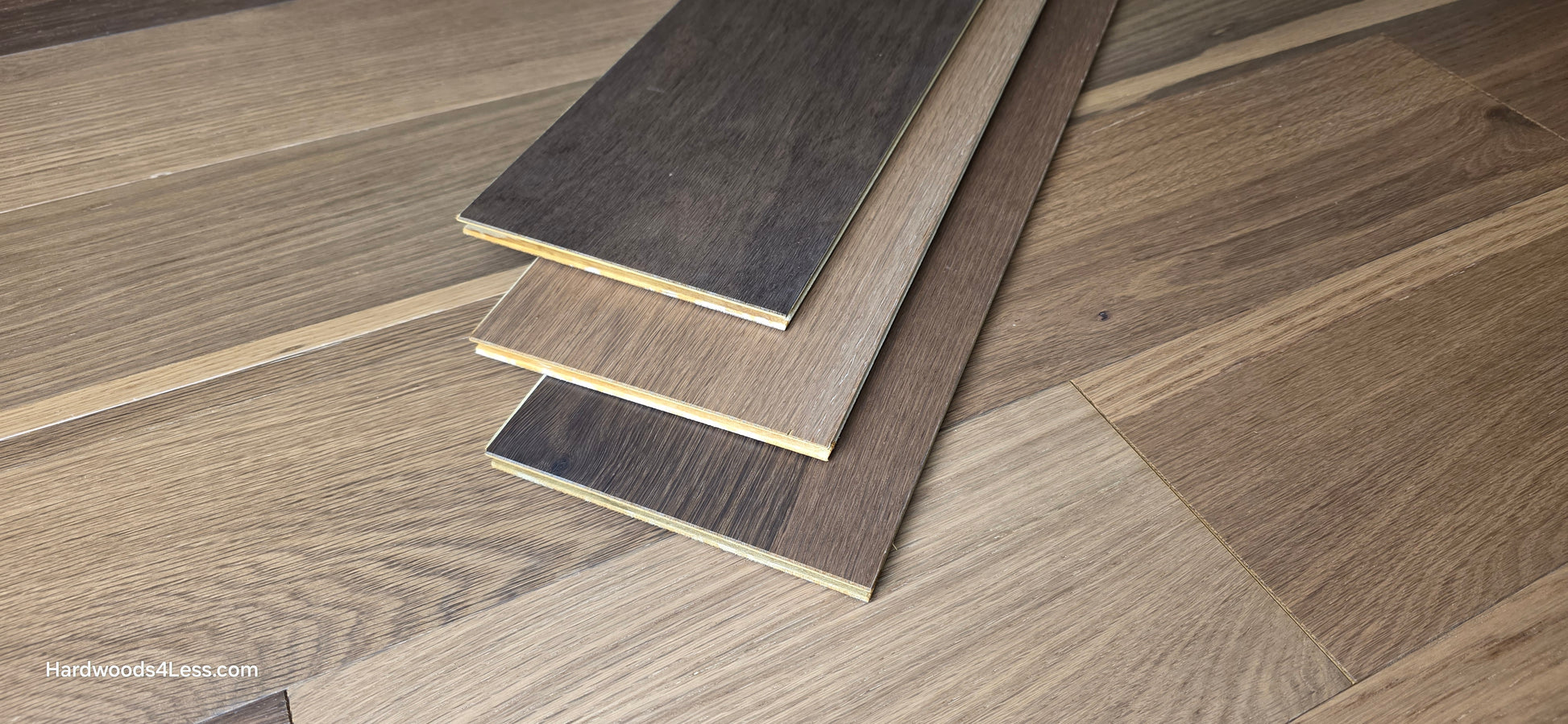 6 1/2" x 7/16" Engineered White Oak Wingham Hardwood Flooring. Shown in the center are 3 planks of the Engineered White Oak flooring. Under the planks is the same hardwood flooring.