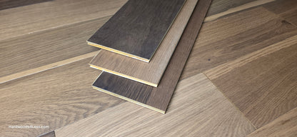 6 1/2" x 7/16" Engineered White Oak Wingham Hardwood Flooring. Shown in the center are 3 planks of the Engineered White Oak flooring. Under the planks is the same hardwood flooring.