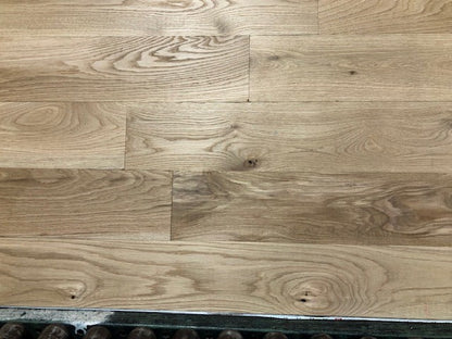 6" x 3/4" Unfinished White Oak #1 Common Solid Hardwood Flooring on a green shooting rack. Rollers can be seen at the base.