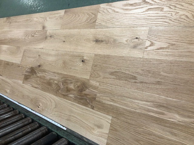 6" x 3/4" Unfinished White Oak #1 Common Solid Hardwood Flooring on a green shooting rack. Rollers can be seen at the base.