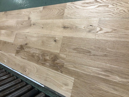 6" x 3/4" Unfinished White Oak #1 Common Solid Hardwood Flooring on a green shooting rack. Rollers can be seen at the base.
