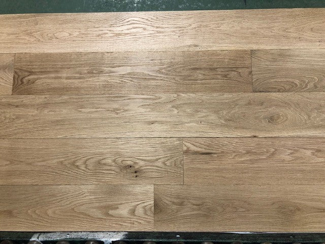 6" x 3/4" Unfinished White Oak #1 Common Solid Hardwood Flooring on a green shooting rack. Rollers can be seen at the base.