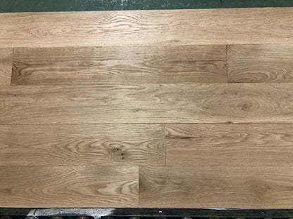 6" x 3/4" Unfinished White Oak #1 Common Solid Hardwood Flooring on a green shooting rack. Rollers can be seen at the base.