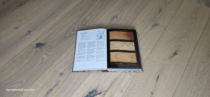 7 1/2" x 1/2" Engineered European White Oak Colmar Hardwood Flooring. Shown with a hardwood book, opened to a random page. The book is resting on top of the Engineered White Oak flooring.