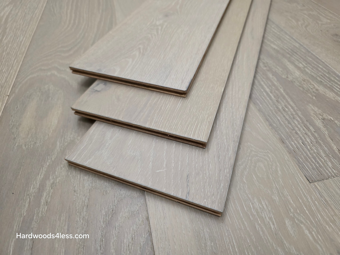 7 1/2" x 9/16" Engineered European Oak Alderney Hardwood Flooring. Shown with three boards stacked in the center of the floor.