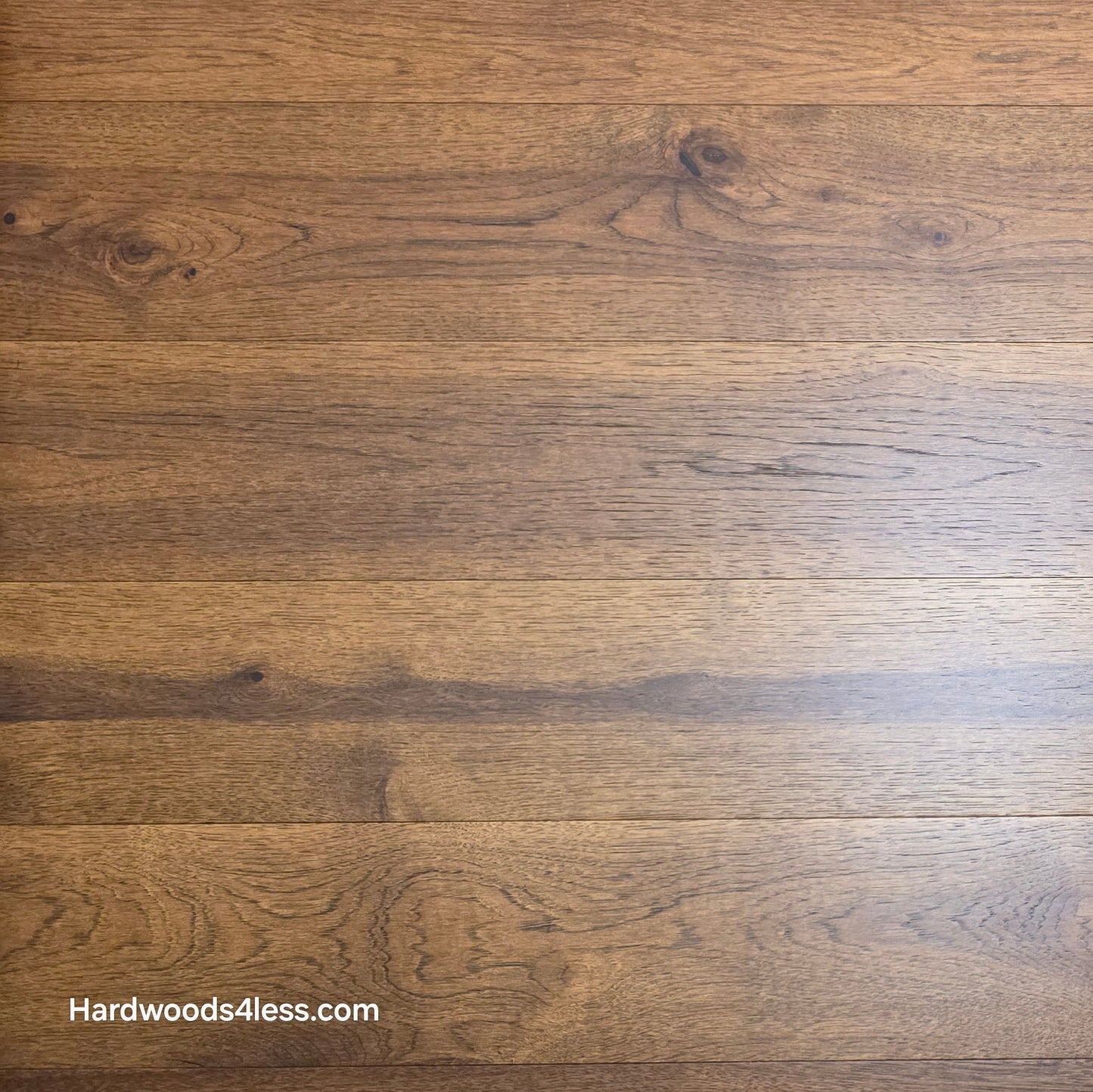 Close-up of 7 1/2" x 9/16" Engineered Hickory Alabay Hardwood Flooring with a visible brand name 'Hardwoods4less.com'.
