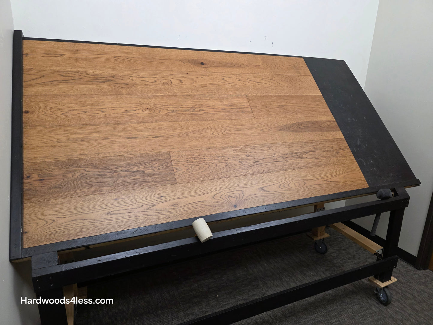 7 1/2" x 9/16" Engineered Hickory English Toffee Hardwood Flooring. Shown on a black shooting table. Shot wide left. 