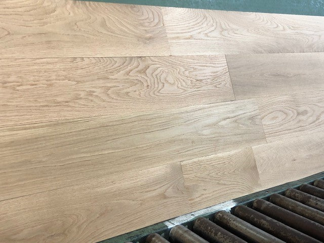 7" x 3/4" Unfinished White Oak Select & Better Solid Hardwood Flooring. Shown on a green shooting table with black rollers on the bottom