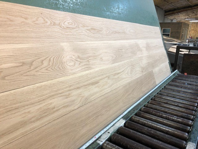 7" x 3/4" Unfinished White Oak Select & Better Solid Hardwood Flooring. Shown on a green shooting table with black rollers on the bottom