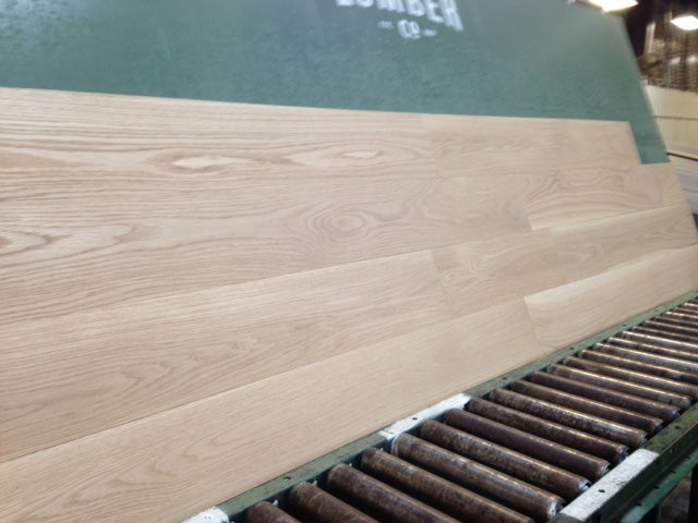 7" x 3/4" Unfinished White Oak Select & Better Solid Hardwood Flooring. Shown on a green shooting table with black rollers on the bottom
