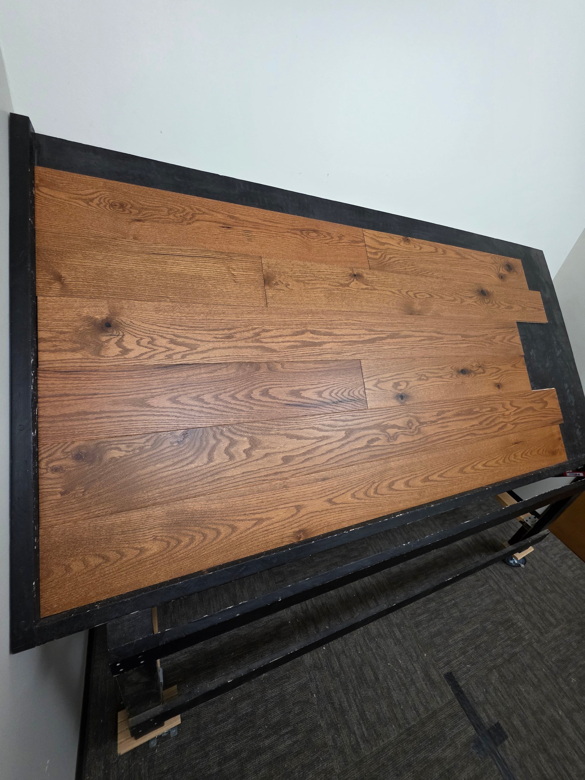 Engineered Red Oak Gunstock Hardwood Flooring on a black table wide shot