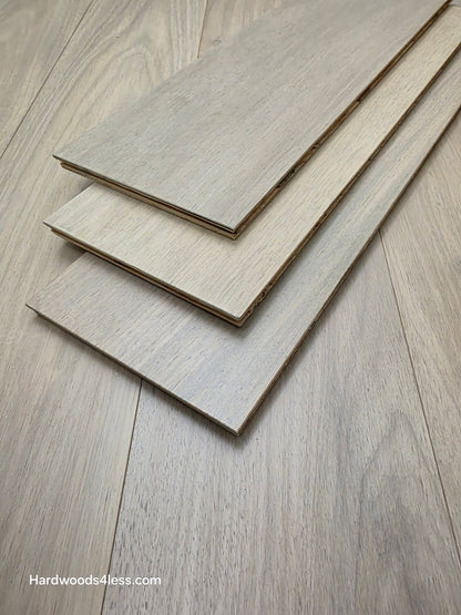7" x 9/16" Engineered Brazilian Oak Mist Hardwood Flooring. Shown as 3 boards stacked on top of the floor. 