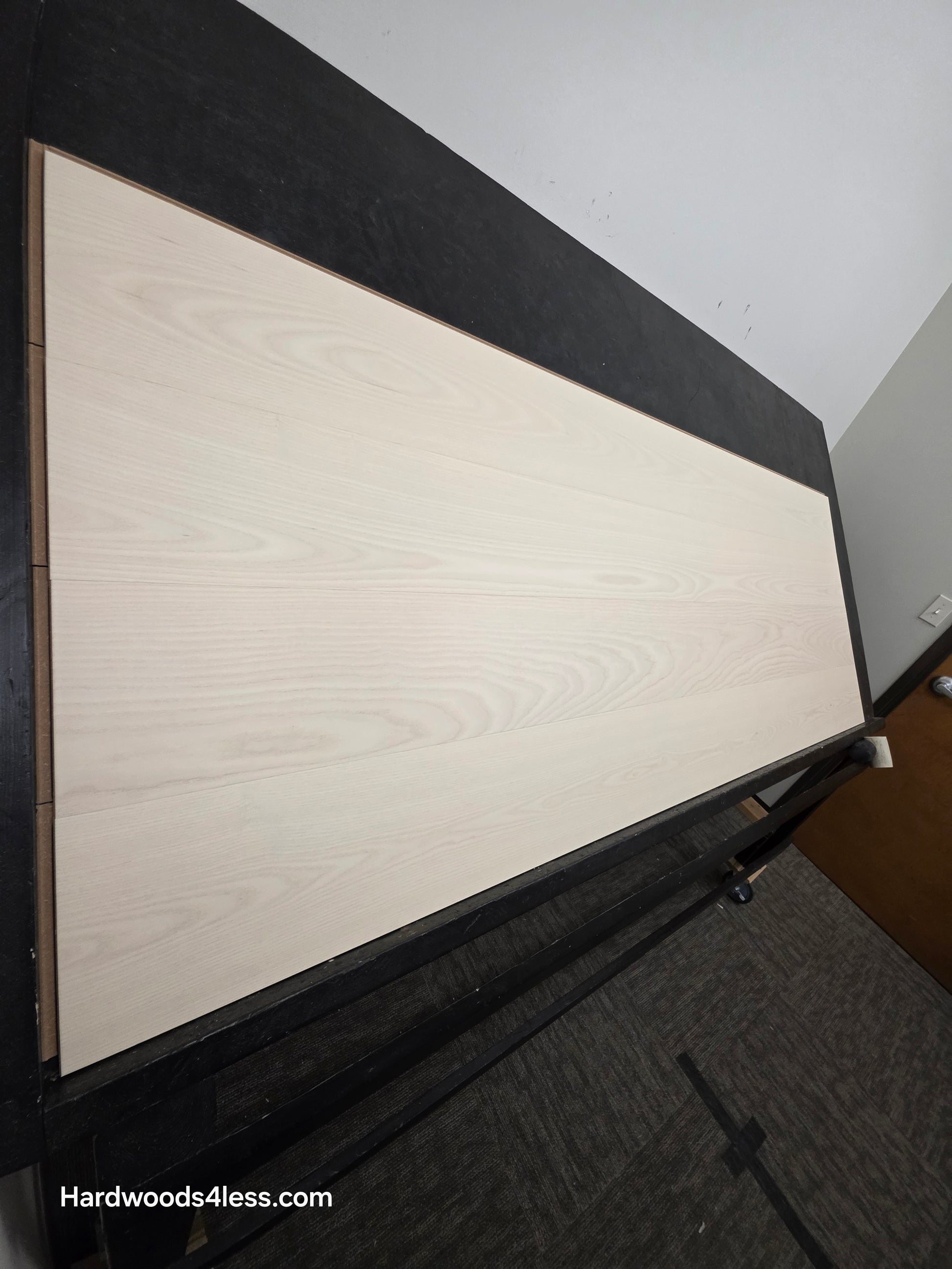 8.11" x 7/16" Modernized Engineered Ash Corbusier Hardened Hardwood Flooring. Shown on a black shooting table. Shot from steep left.