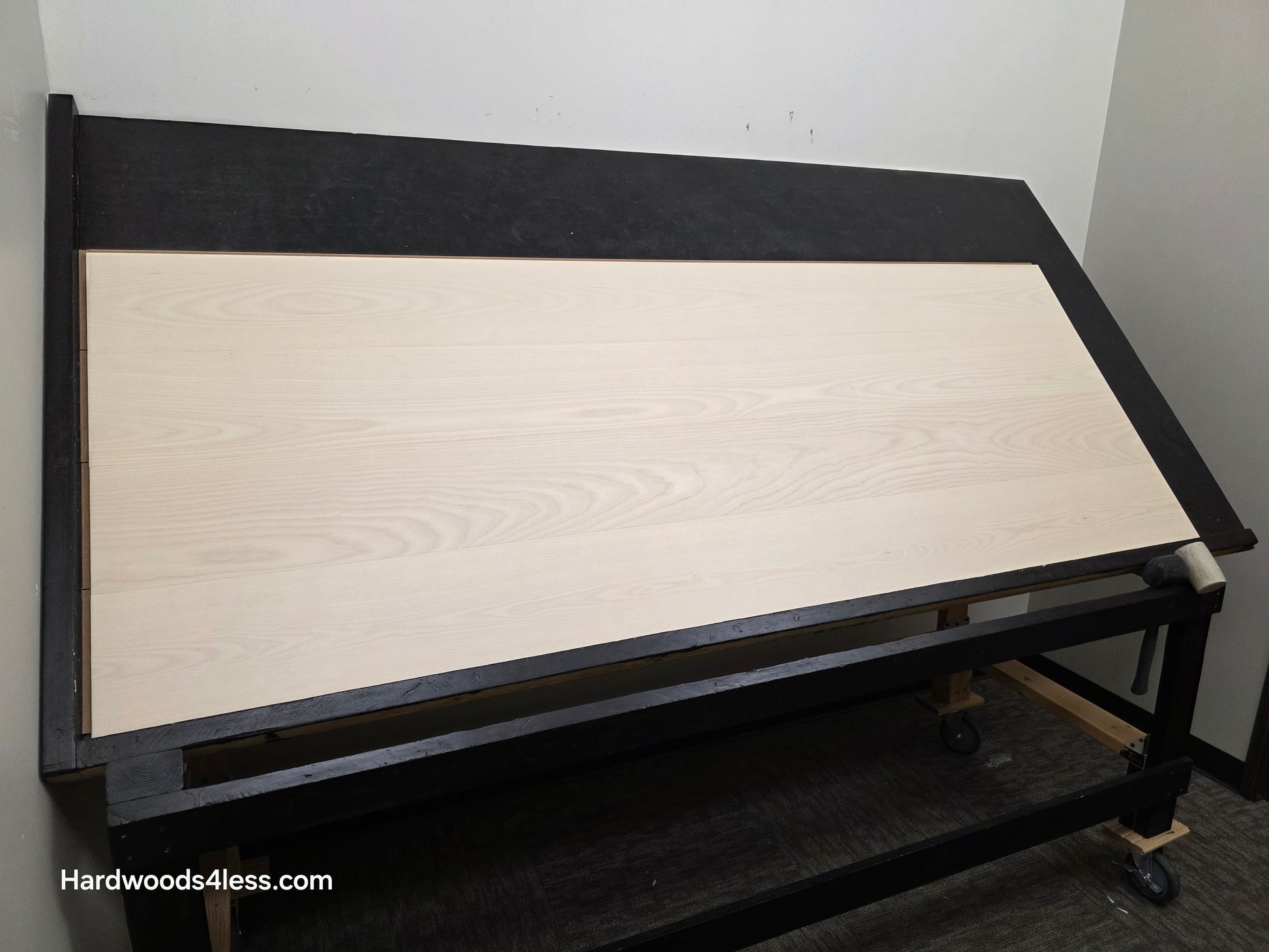 8.11" x 7/16" Modernized Engineered Ash Corbusier Hardened Hardwood Flooring. Shown on a black shooting table. Shot from wide left.