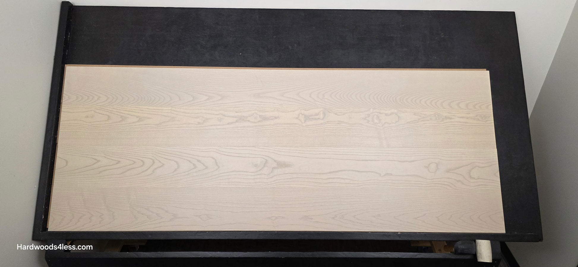 8.11" x 7/16" Modernized Engineered Ash Foster Hardened Hardwood Flooring. Shown on a black shooting table. Shot from center.