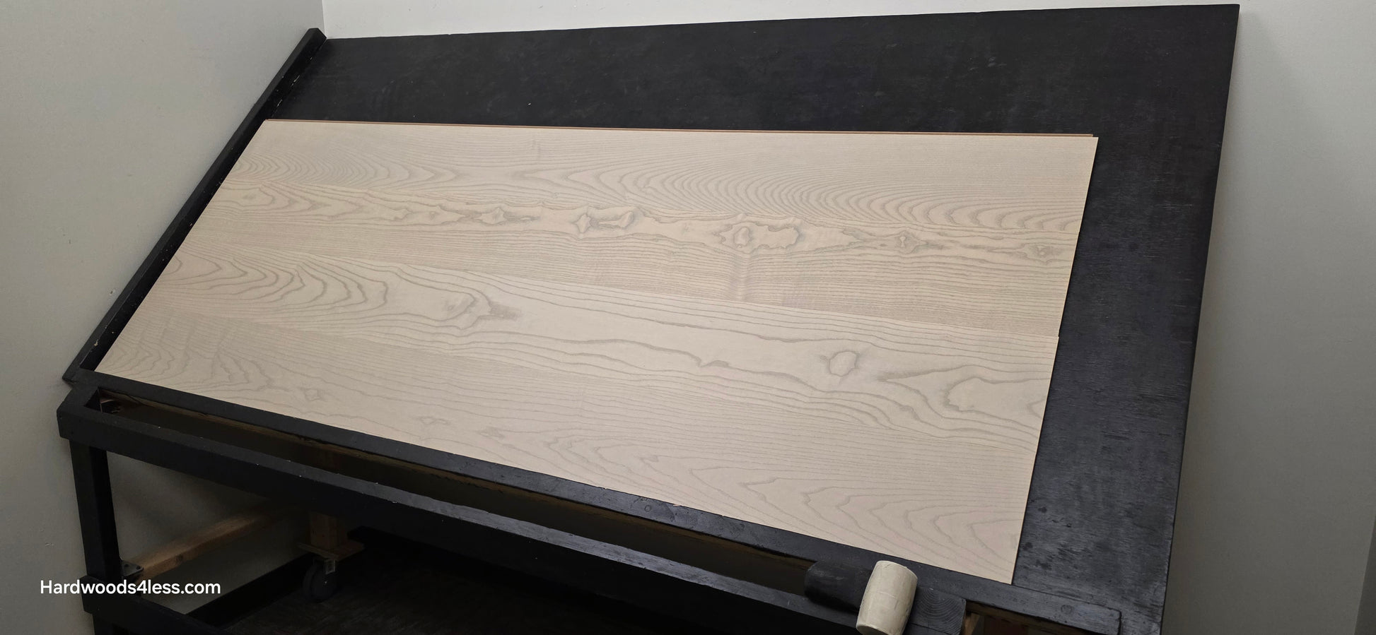 8.11" x 7/16" Modernized Engineered Ash Foster Hardened Hardwood Flooring. Shown on a black shooting table. Shot from wide right.