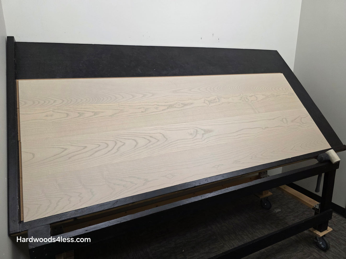 8.11" x 7/16" Modernized Engineered Ash Foster Hardened Hardwood Flooring. Shown on a black shooting table. Shot from wide left. 