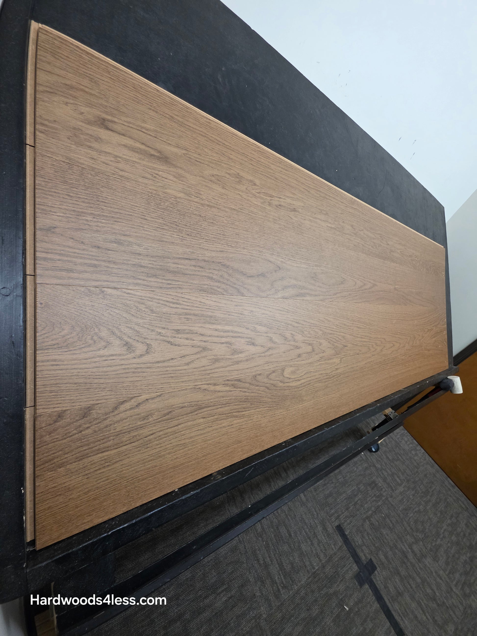 8.11" x 7/16" Modernized Engineered European Oak Calatrava Hardened Hardwood Flooring. Shown on a black shooting table. Shot from steep left. 