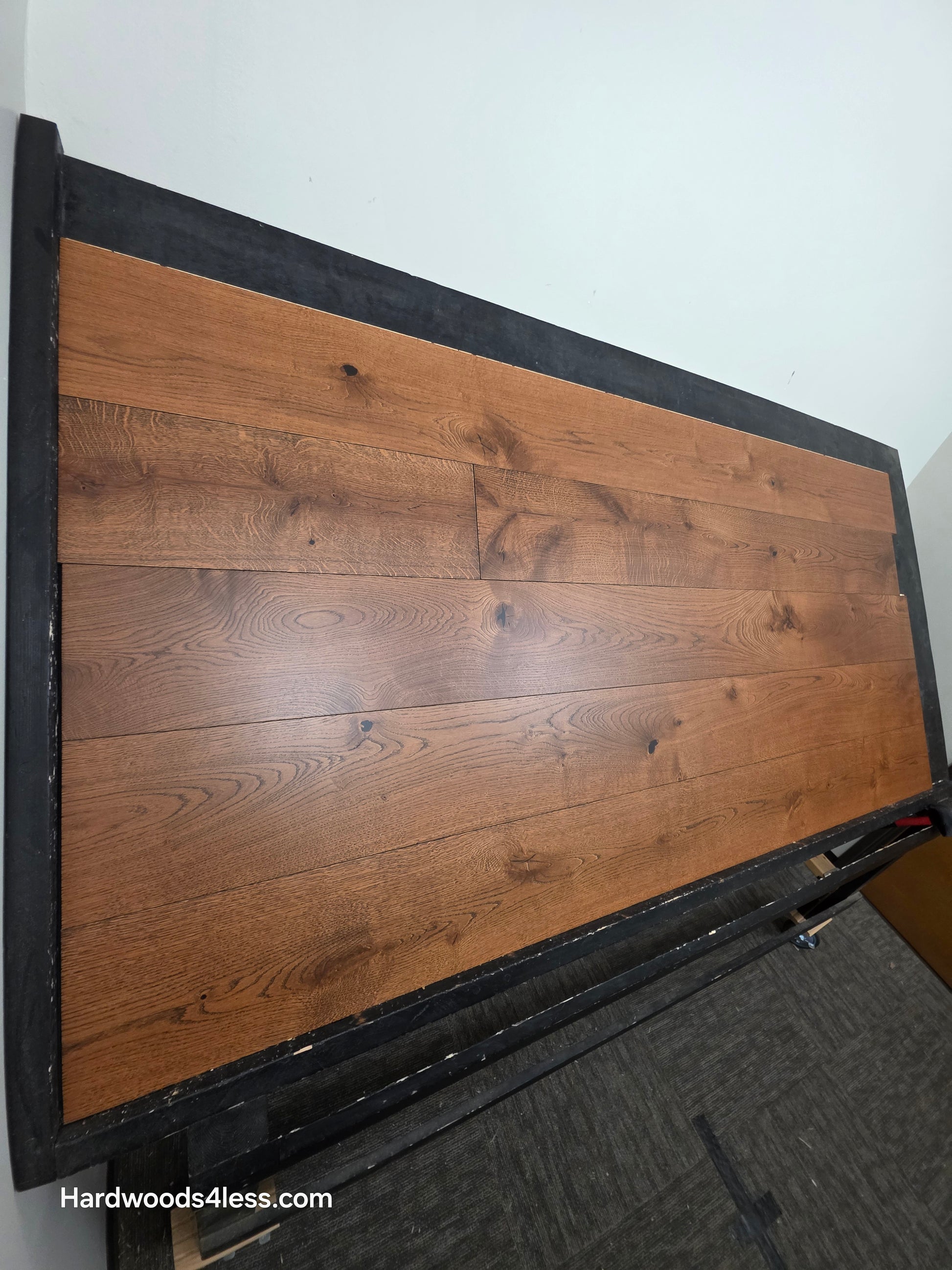 8 1/4" x 9/16" Engineered European Oak Corinth Hardwood Flooring. Shown on a black shooting rack. Shot wide left.