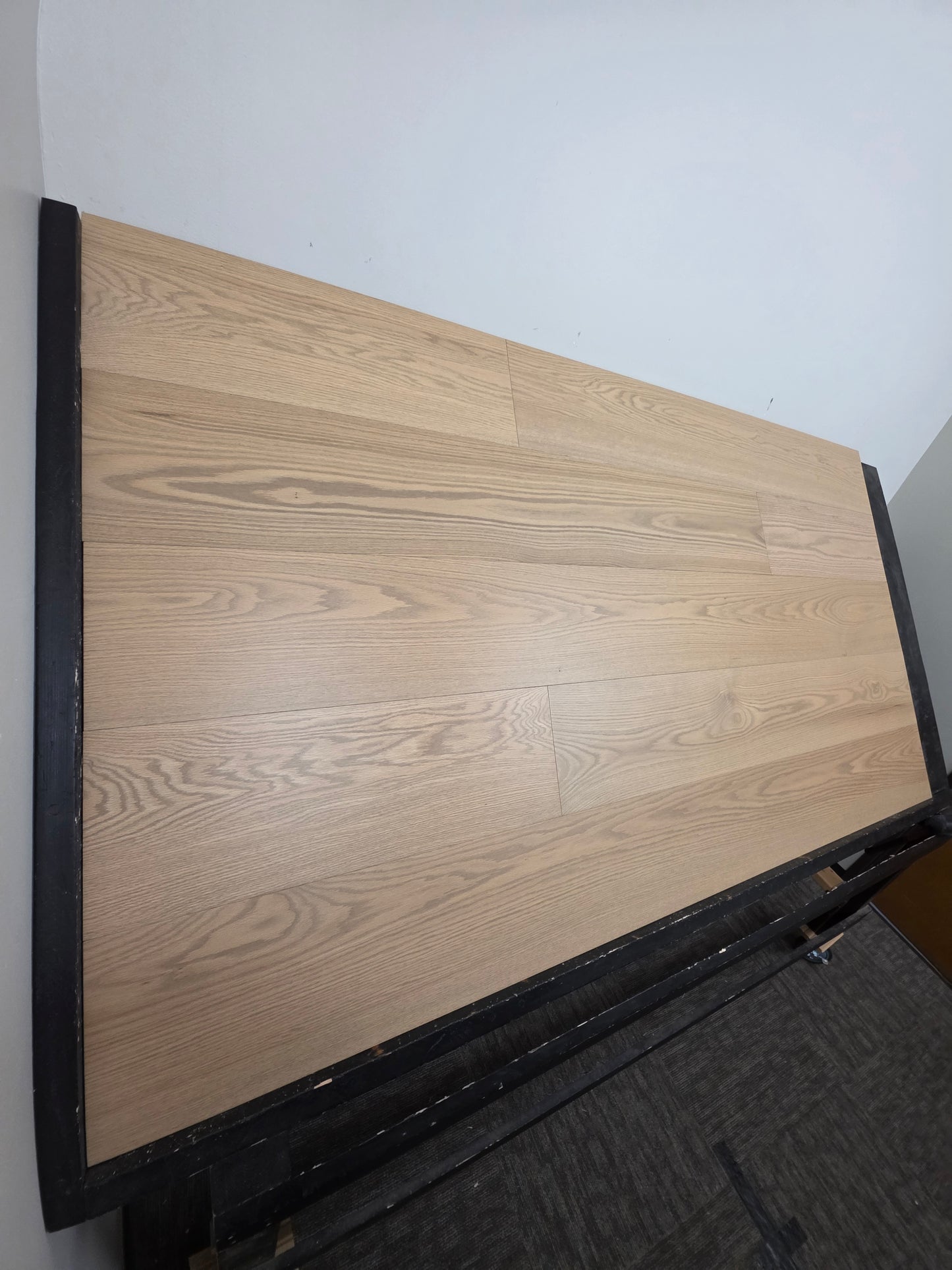 9 1/2" x 5/8" Engineered White Oak Finch Hardwood Flooring. Shown  on a black shooting table steep left angle. 