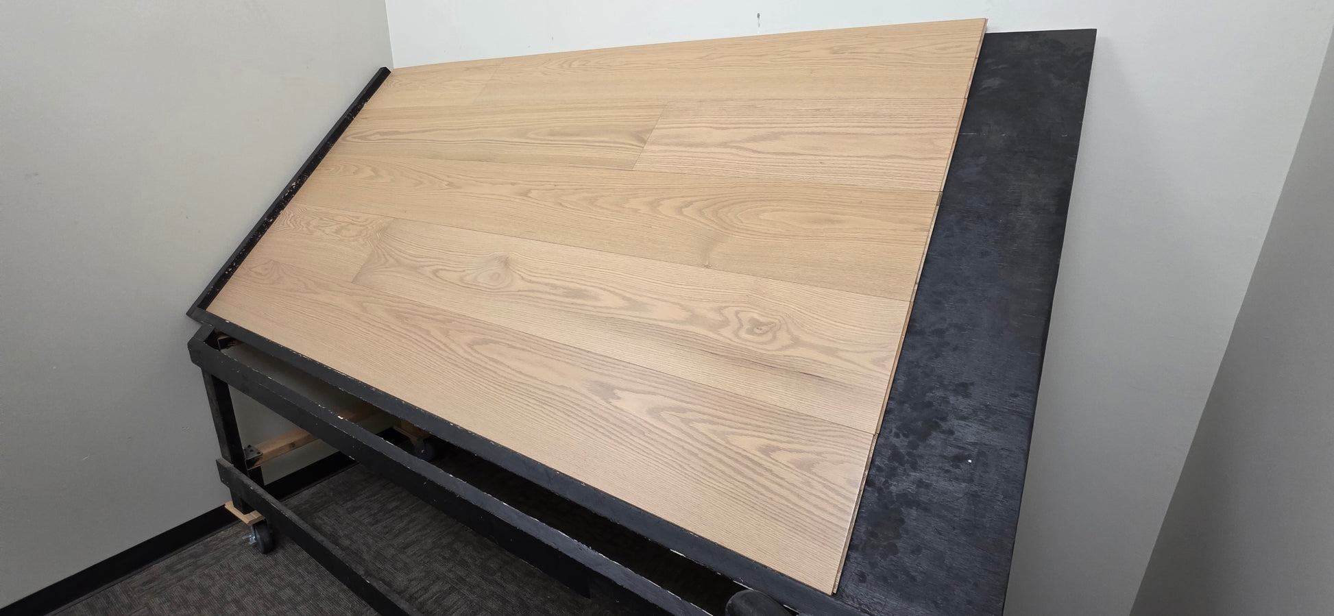 9 1/2" x 5/8" Engineered White Oak Finch Hardwood Flooring. Shown  on a black shooting table. Wide righthand shot. 