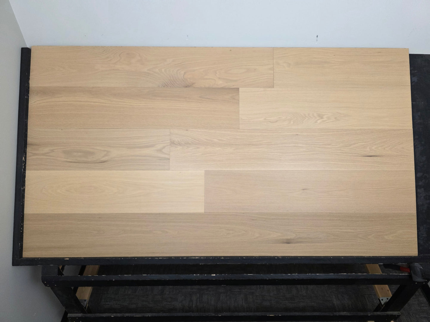 9 1/2" x 5/8" Engineered White Oak Sparrow Hardwood Flooring shown head on. Placed on a black shooting rack.